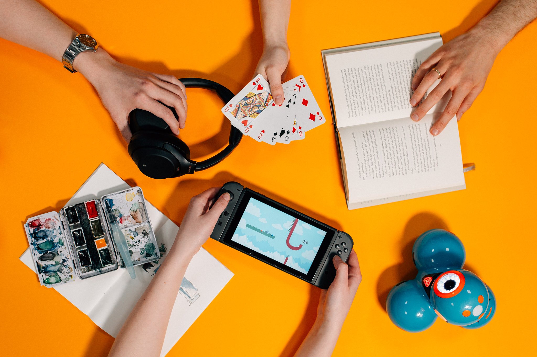 Hände halten Handy, Spielkarten und ein Buch