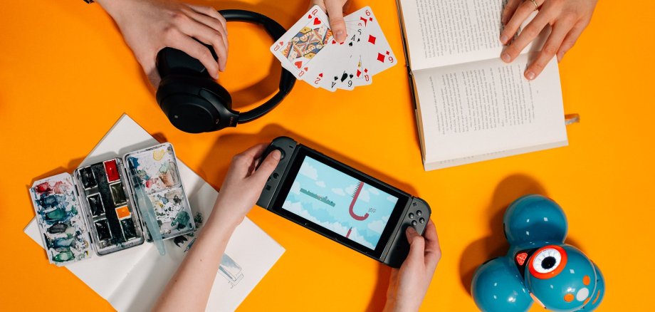 Hände halten Handy, Spielkarten und ein Buch