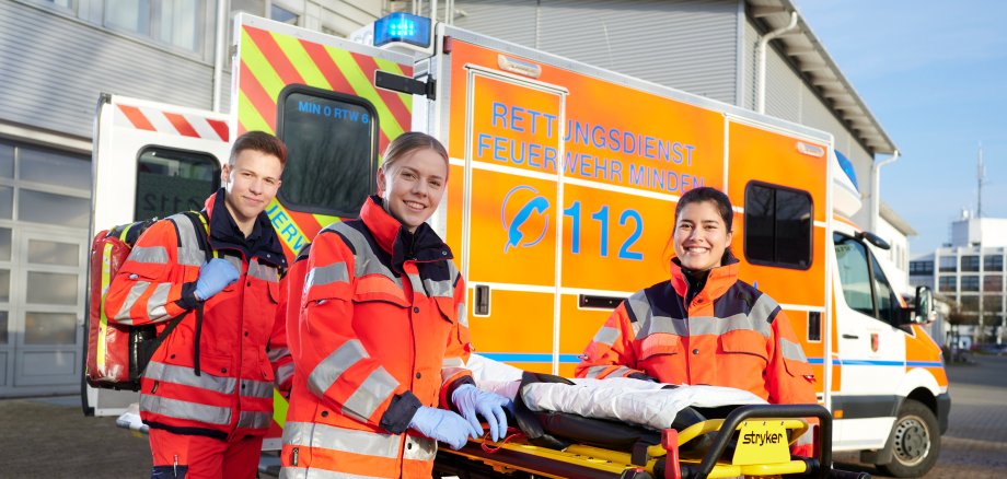 Junge Rettungssanitäter*innen vor einem Rettungswagen