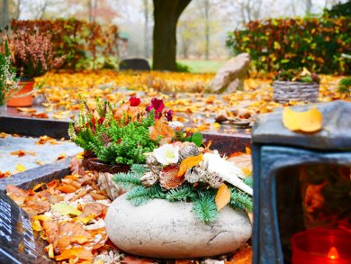 Friedhof im Herbst Ein Gesteck auf einem Grab mit bunten Blättern