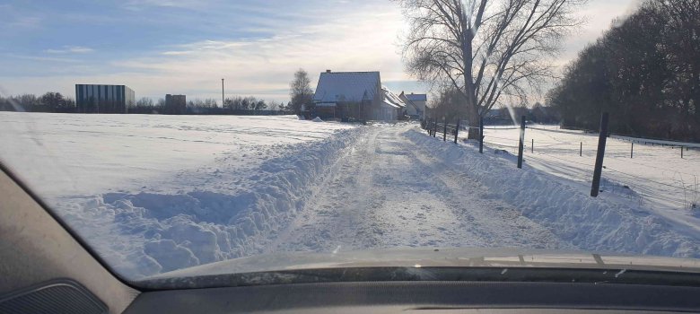Eine verschneite Straße, auf der Schnee geräumt wurde. 