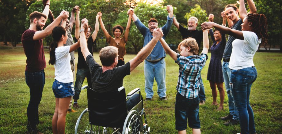 Eine Gruppe Menschen im Park hält sich an den Händen