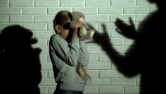 Häusliche Gewalt ängstliches Kind schützt sich mit Teddybären vor drohenden Schatten Erwachsener