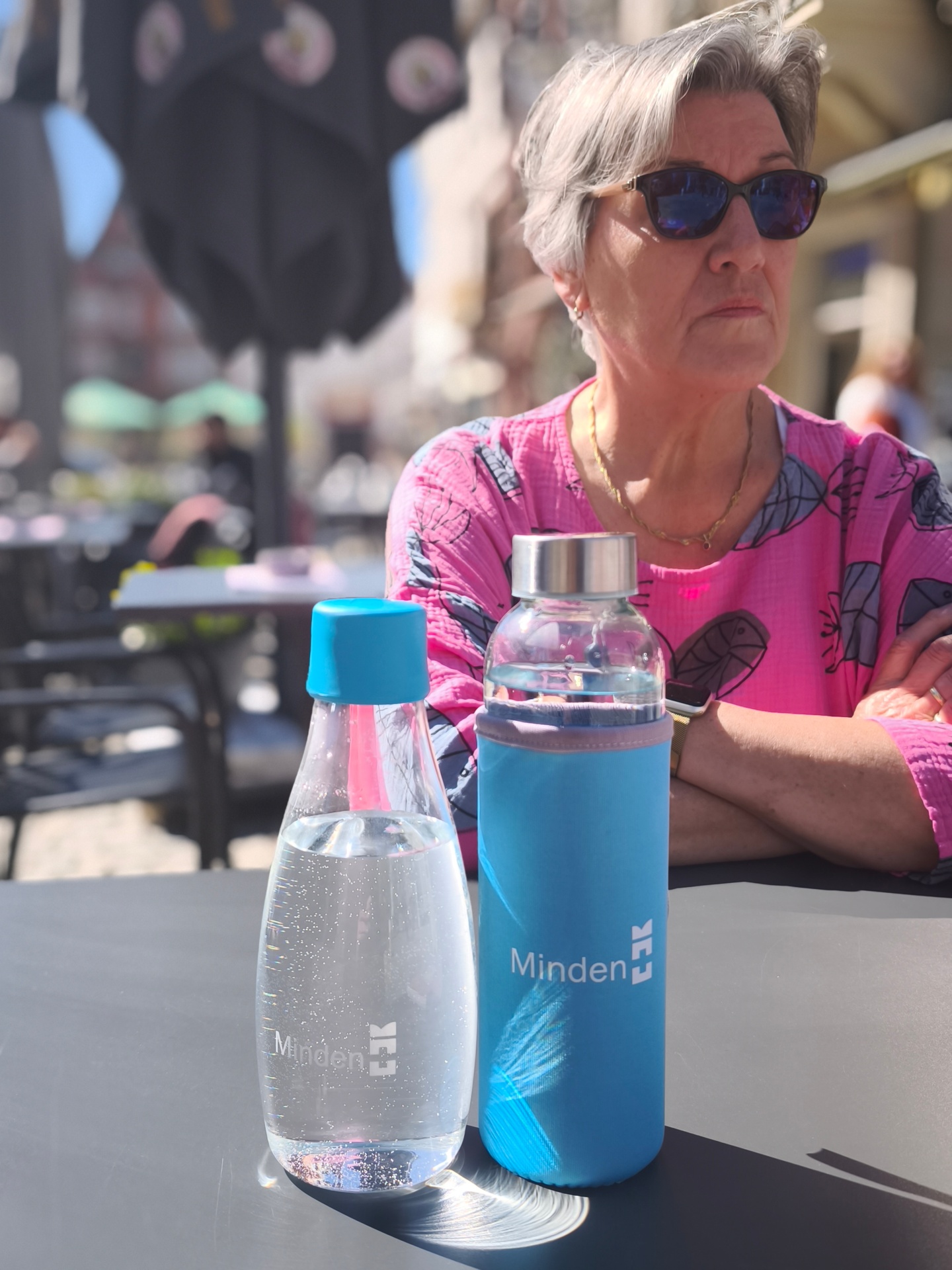 Hitze Senior*innen Frau sitzt an Tisch mit Wasserflaschen