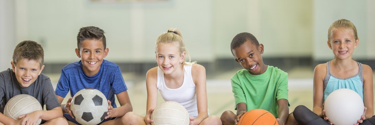 Kinder sitzen in einer Gruppe beim Sport.