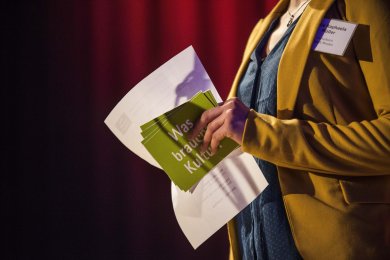 Moderatorin hält Karte und Mikrofon in der Hand