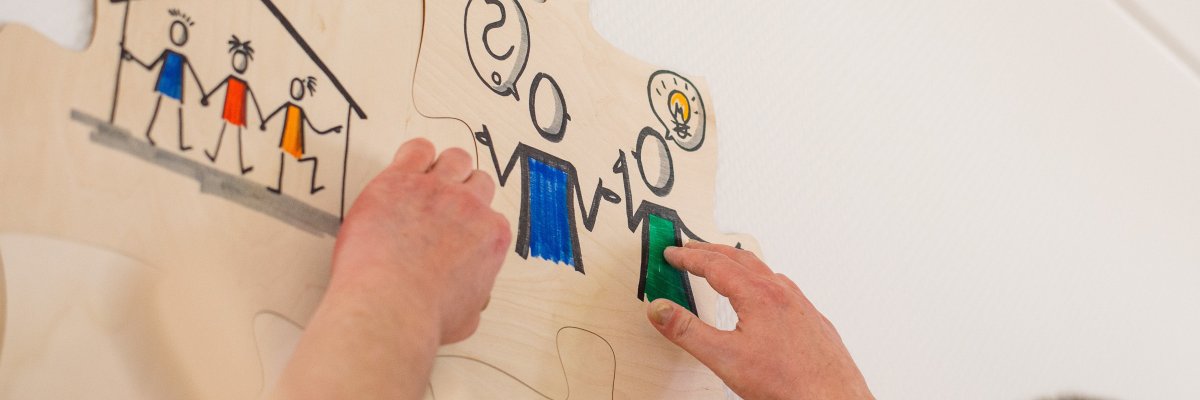 Jemand hängt ein Puzzleteil mit einer Zeichnung auf