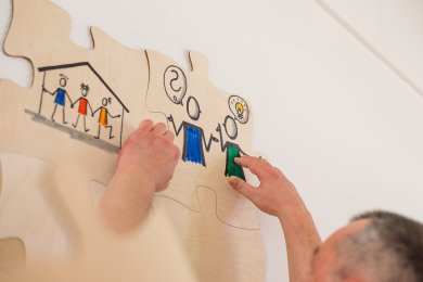 Miteinander reden Jemand hängt ein Puzzleteil mit einer Zeichnung auf