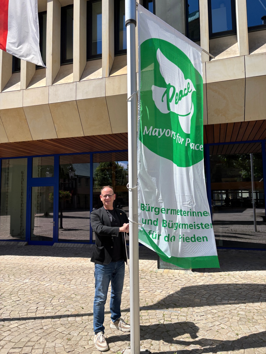Bürgermeister Peter Kock hisst zum Mayors for Peace-Tag die Flagge am Rathaus