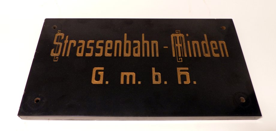 Schild mit der Aufschrift „Strassenbahn - Minden G. m. b. H. Schild mit der Aufschrift „Strassenbahn - Minden G. m. b. H.“.