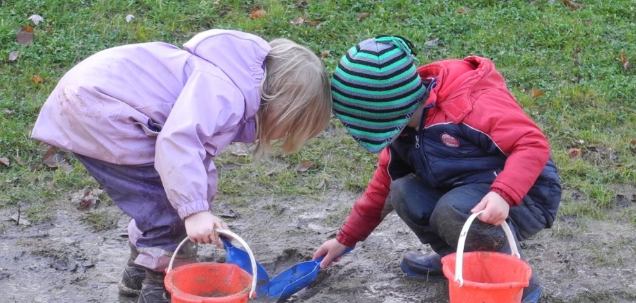 Kita-Kinder spielen draußen im Matsch