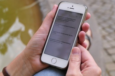 RSS-Feed Nachrichtenticker Newsletter Eine Frau hält ein Smartphone mit einem geöffneten Newsletter in der Hand