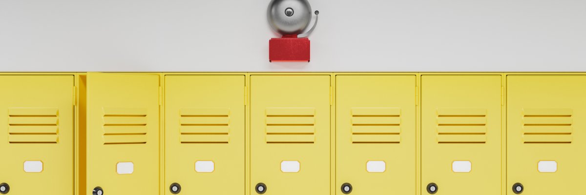 Eine Reihe gelber Spintschränke mit einer Schulglocke