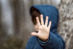 Schutz vor Gewalt, Verteidigung ein Junge hebt schützend die Hand