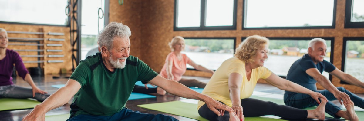 Eine Gruppe Senior_innen in einem Yoga-Kurs