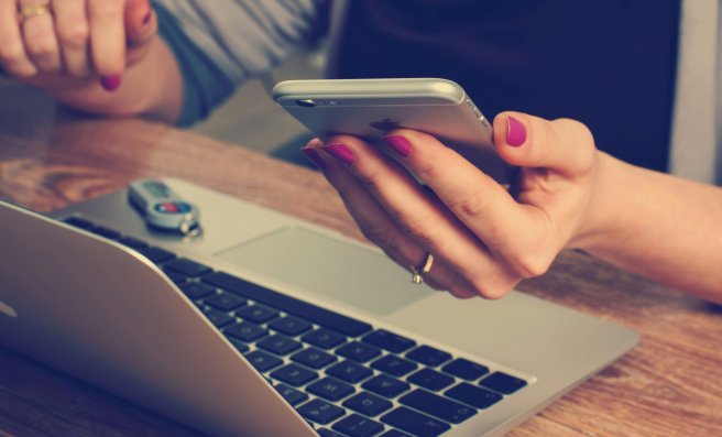Person mit offenem Laptop und Smartphone