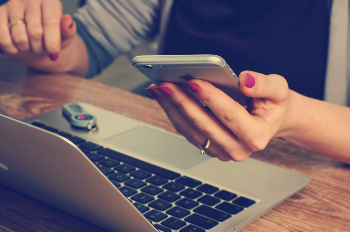 Person mit offenem Laptop und Smartphone