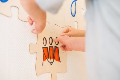 Zusammenarbeit stärken Zwei Menschen halten ein großes Puzzlestück aus Holz